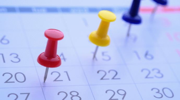 Calendar with thumbtacks marking dates