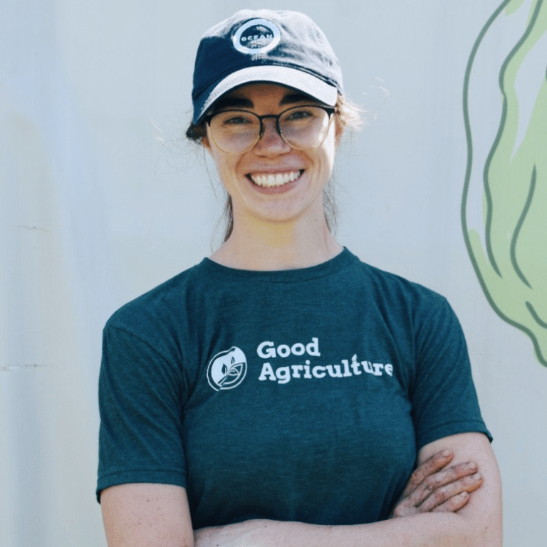 Alex Edquist, CEO and co-founder of Good Agriculture, smiling in a Good Agriculture shirt and hat during an outdoor agriculture and farm business team photoshoot.
