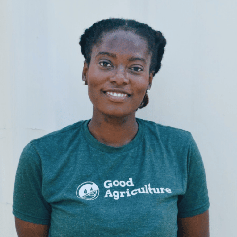 Reba Liddy, Marketing and Sales Manager at Good Agriculture, smiling in a Good Agriculture shirt during an outdoor farm and agriculture team photoshoot.